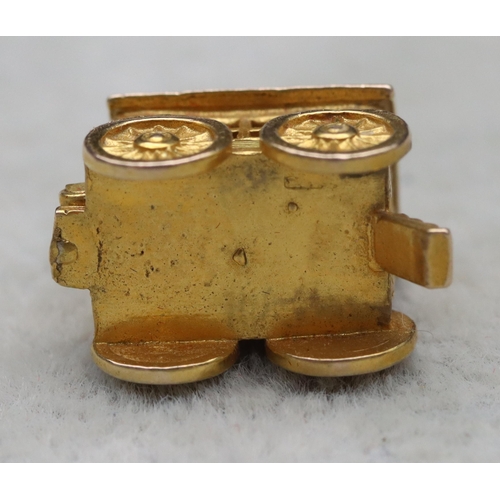 699 - A 9ct gold charm in the form of a Gypsy caravan with hinge top enclosing figure, 4 grams