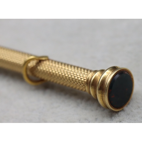 700 - S Morden & Co. gold propelling pencil with allover engine turned decoration and seal motif to top, 9... 