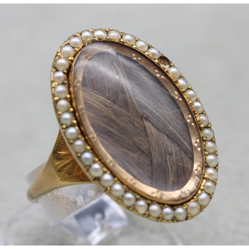 703 - An 18th Century Mourning gold ring with oval top, inset with plaited hair surrounded by half pearls ... 