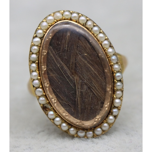 703 - An 18th Century Mourning gold ring with oval top, inset with plaited hair surrounded by half pearls ... 