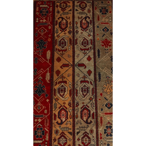 828 - A Persian rug on red and blue ground with 4 centre strips with hook and floral design, 131cm x 83cm