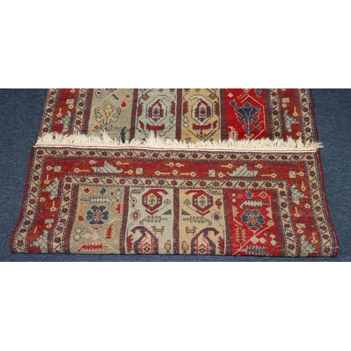 828 - A Persian rug on red and blue ground with 4 centre strips with hook and floral design, 131cm x 83cm