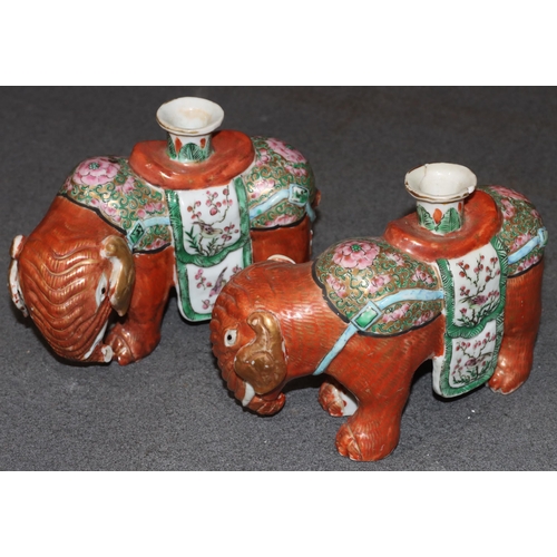 107 - A pair of Chinese candlesticks in the form of elephants on red ground with Cantonese style decoratio... 