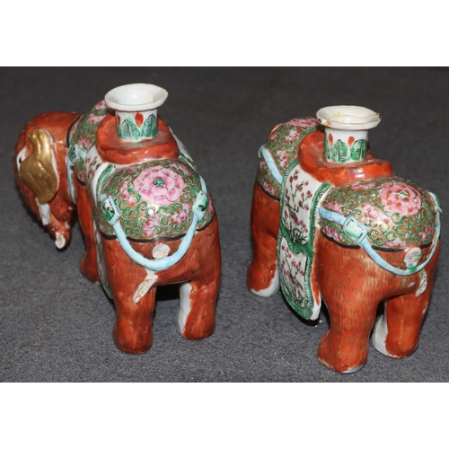 107 - A pair of Chinese candlesticks in the form of elephants on red ground with Cantonese style decoratio... 