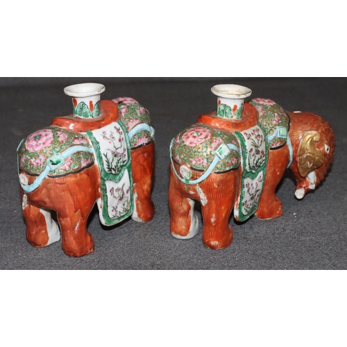 107 - A pair of Chinese candlesticks in the form of elephants on red ground with Cantonese style decoratio... 