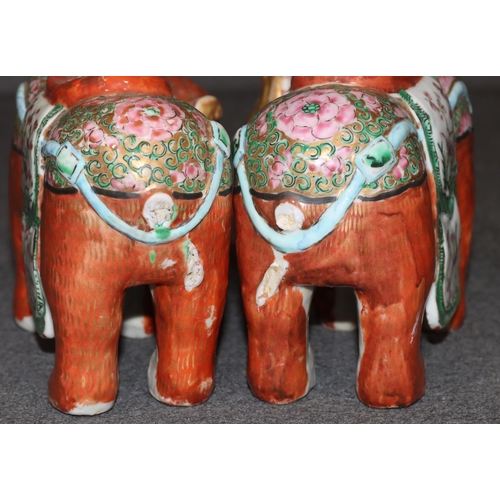 107 - A pair of Chinese candlesticks in the form of elephants on red ground with Cantonese style decoratio... 