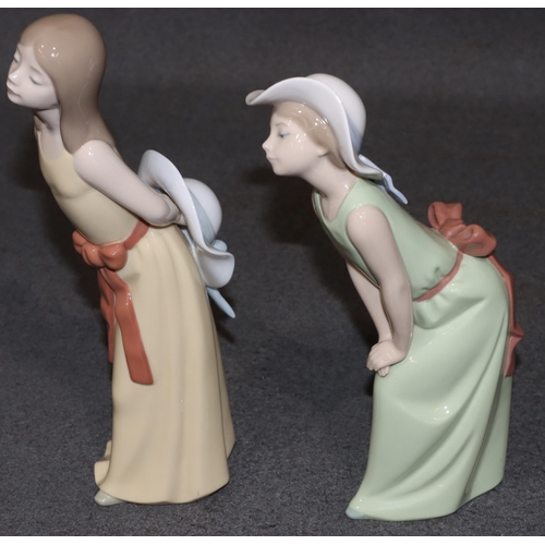 127 - 2 Lladro figures of standing young ladies holding hats in yellow and green dresses, largest 24cm hig... 