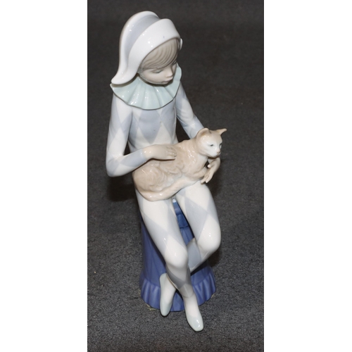 131 - A Lladro figure of a seated young boy dressed as a jester holding a cat, 23cm high