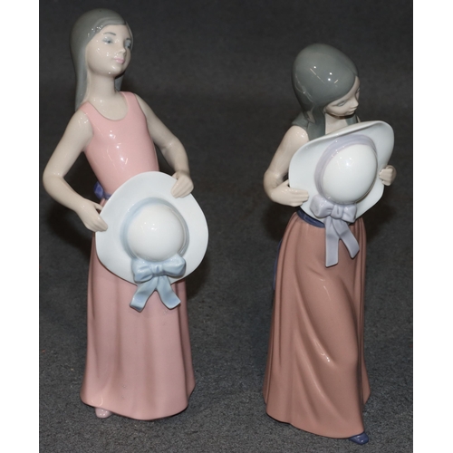 132 - 2 Lladro figures of standing young ladies holding hats, wearing pink dresses, largest 25.5cm high (2... 