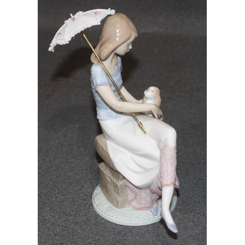 139 - A Lladro figure of a young seated lady with dog and parasol (parasol loose), 21cm high (boxed)