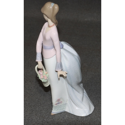 140 - A Lladro figure of a standing young lady holding a basket of encrusted flowers, 24.5cm high (boxed)