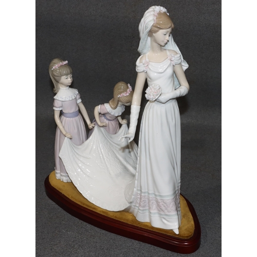 143 - A large Lladro group of a bride attended by 2 bridesmaids holding her train, on wooden base, 37cm hi... 