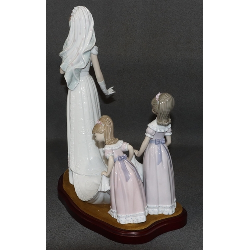 143 - A large Lladro group of a bride attended by 2 bridesmaids holding her train, on wooden base, 37cm hi... 