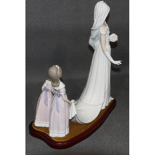 143 - A large Lladro group of a bride attended by 2 bridesmaids holding her train, on wooden base, 37cm hi... 