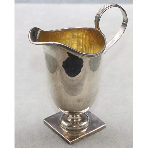 353 - A George V silver helmet shaped cream jug with scroll handle and reeded rim on square base, London 1... 