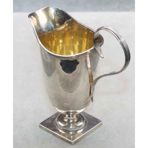 353 - A George V silver helmet shaped cream jug with scroll handle and reeded rim on square base, London 1... 