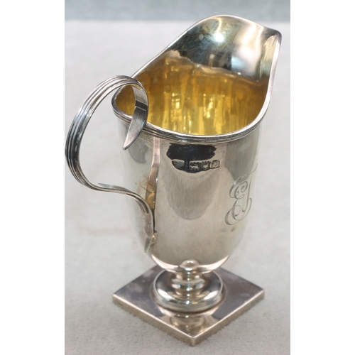 353 - A George V silver helmet shaped cream jug with scroll handle and reeded rim on square base, London 1... 