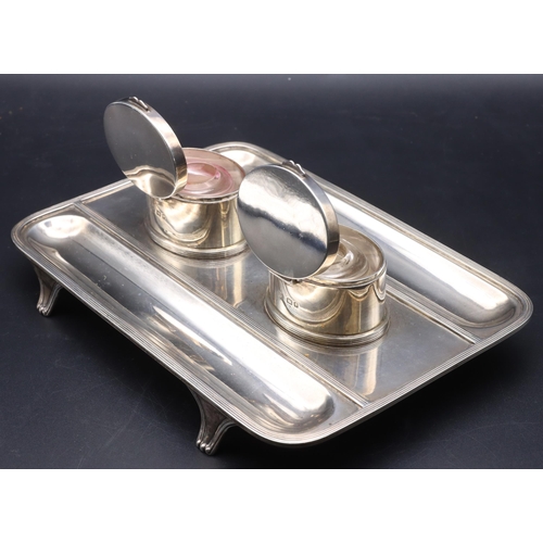 399 - A George V silver rectangular shaped inkwell with 2 oval lidded oval inkwells enclosing glass liners... 