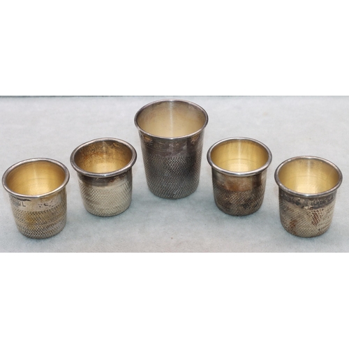 406 - A set of 4 silver plated shot glasses in the form of thimbles and a similar larger thimble (5)