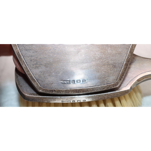 450 - A Birmingham silver small hand mirror with engine turned decoration with matching brush (2)