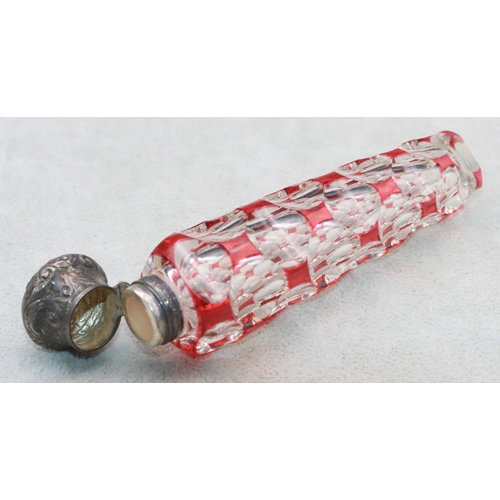 483 - A ruby and clear glass scent bottle with allover thumb decoration with embossed floral and scroll de... 