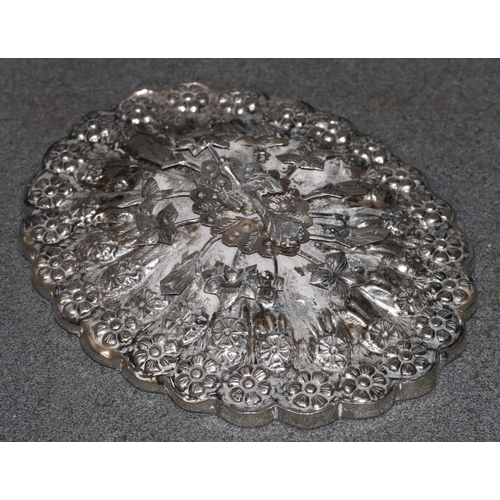 491 - An Eastern silver coloured metal oval scallop shaped hand mirror with raised and embossed bird, flor... 