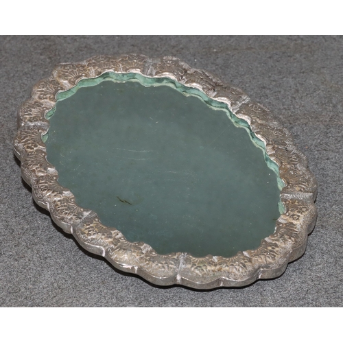 491 - An Eastern silver coloured metal oval scallop shaped hand mirror with raised and embossed bird, flor... 