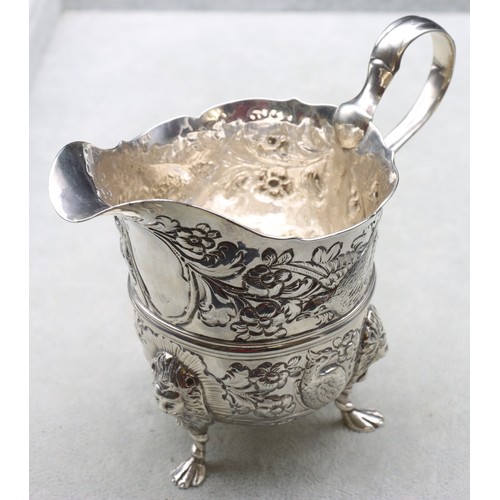 289 - A George V silver milk jug with allover embossed bird, floral and leaf decoration, scroll handle on ... 