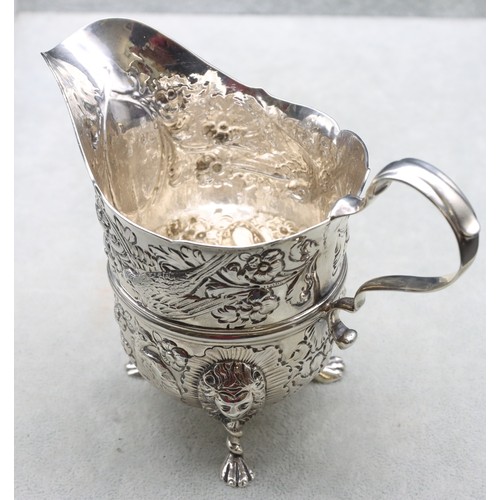 289 - A George V silver milk jug with allover embossed bird, floral and leaf decoration, scroll handle on ... 