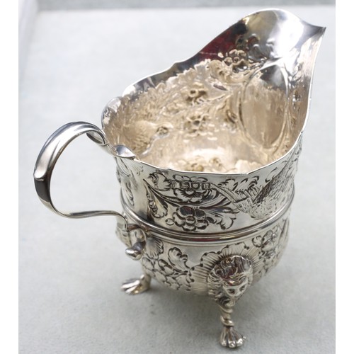 289 - A George V silver milk jug with allover embossed bird, floral and leaf decoration, scroll handle on ... 