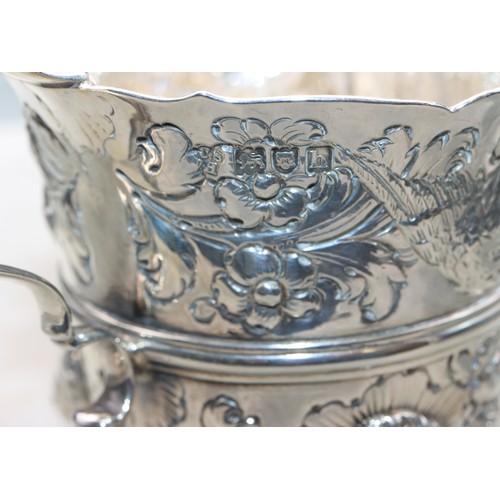 289 - A George V silver milk jug with allover embossed bird, floral and leaf decoration, scroll handle on ... 