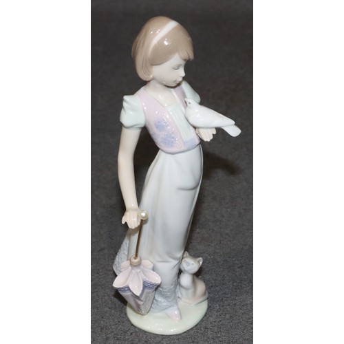 180 - A Lladro figure of a young standing lady, holding a dove with cat and closed parasol at her feet, 22... 