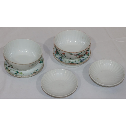 107 - A pair of Oriental round bulbous lidded bowls with saucers on white ground with multi-coloured flora... 