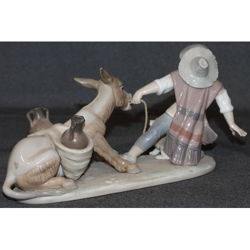 28 - A Lladro group of figure and dog pulling donkey (boy's right arm restored), 28cm long, 14cm high