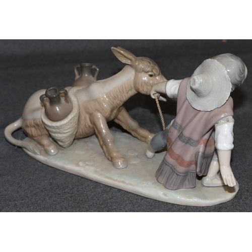 28 - A Lladro group of figure and dog pulling donkey (boy's right arm restored), 28cm long, 14cm high