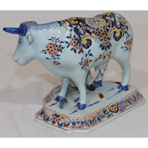 88 - A Dutch Delft group of seated figure milking a cow on white and blue ground with multi-coloured flor... 