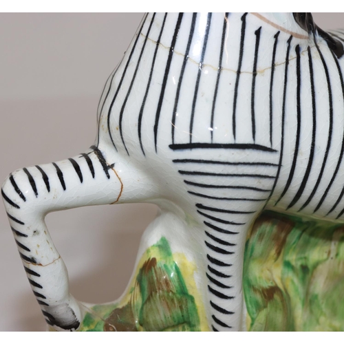 90 - A 19th Century Staffordshire figure of a Zebra, 22.5cm high (crack around neck and top front right l... 