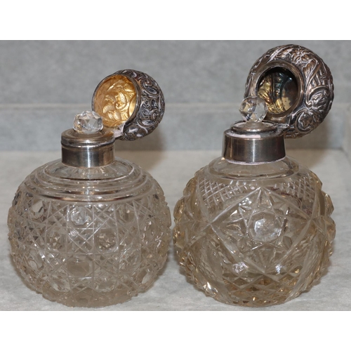 244 - 2 cut glass round bulbous shaped scent bottles with Birmingham silver hinged floral and scroll decor... 