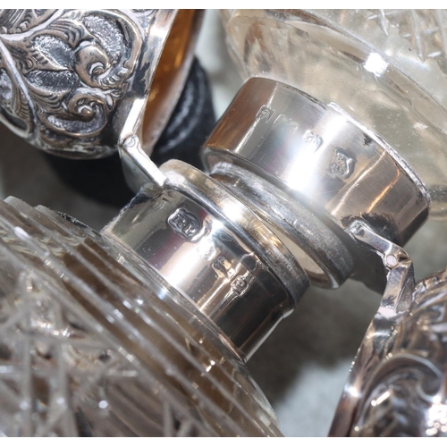 244 - 2 cut glass round bulbous shaped scent bottles with Birmingham silver hinged floral and scroll decor... 