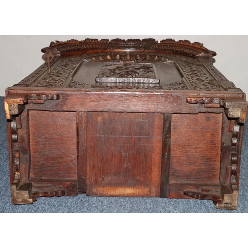 732 - An oak domed table topped cabinet, single panel door with raised carved and pierced figure, leaf and... 