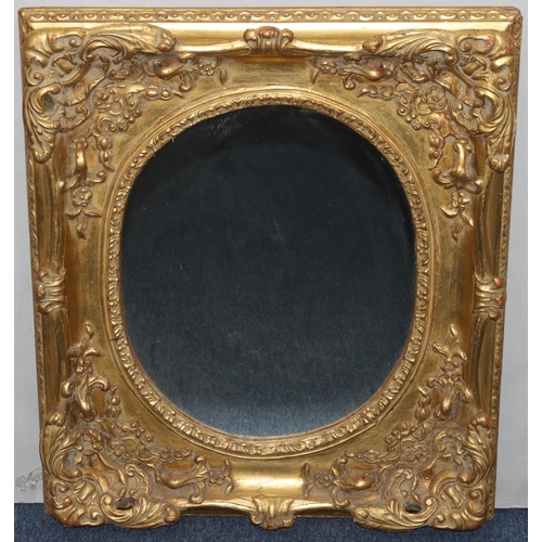 739 - A gilt hanging oval wall mirror with raised floral, leaf and scroll decoration, 73cm x 63cm