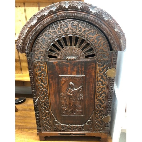 732 - An oak domed table topped cabinet, single panel door with raised carved and pierced figure, leaf and... 