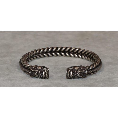 454 - An Oriental silvered metal bangle with 2 dragon heads