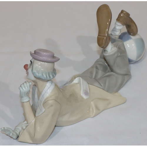 110 - A Lladro group of a resting clown with his foot on a ball, 37cm long, 16cm high