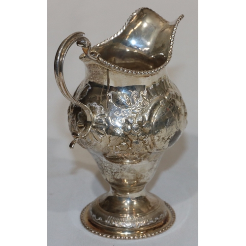 200 - An early George III silver round bulbous shaped milk jug with ball rim and allover embossed bird, fl... 