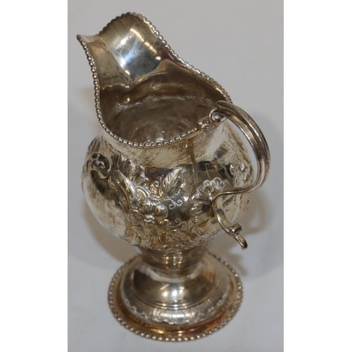 200 - An early George III silver round bulbous shaped milk jug with ball rim and allover embossed bird, fl... 