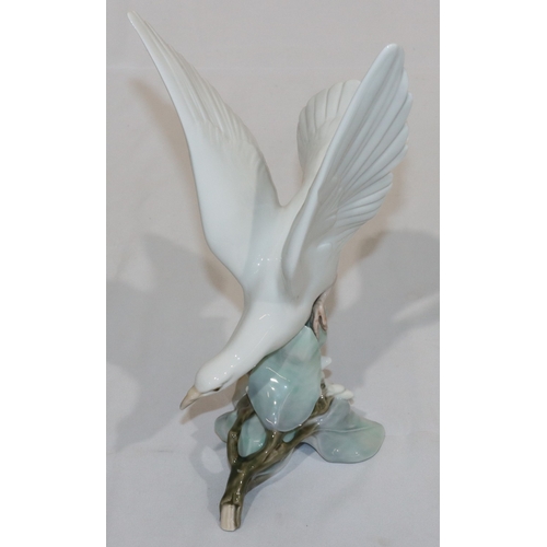 25 - A Lladro figure of a white bird perched on branch, 28cm high