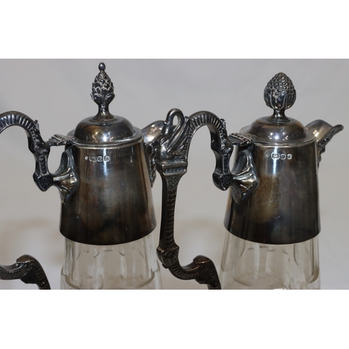 257 - A pair of modern cut glass claret jugs with silver necks, hinged lids, scroll handles and mask head ... 