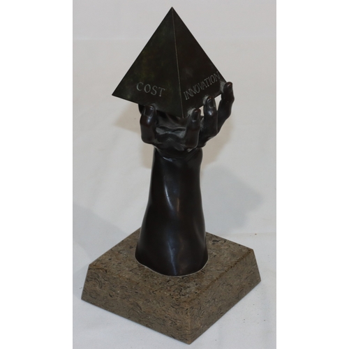 686 - A bronze sculpture of a hand holding a pyramid, marked 