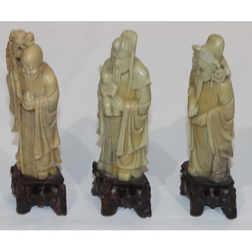 690 - 3 Oriental soapstone figures of standing gentlemen holding staffs etc., on pierced bases, 15cm high